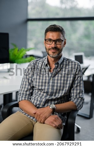 Close up of Cheerful Male Boss With Beard and Glasses Looking to Camera and Smiling. Good Looking Caucasian Man Team Leader in Modern Company Office. Portraits. Concept of People and Emotions Royalty-Free Stock Photo #2067929291