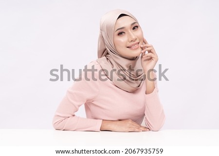 A beauty shot of a pretty young hijab girl with smooth glowing skin relaxing on a table over white background studio. Beauty skin care concept. Royalty-Free Stock Photo #2067935759