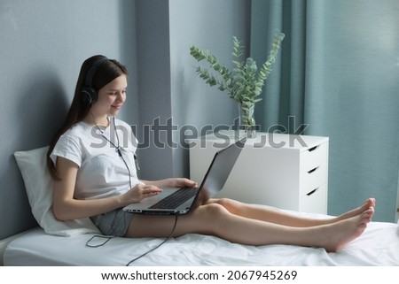 teen school girl student virtual distance learning online digital class looking at laptop sitting on bed at home. High quality photo