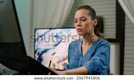 Woman working as editor with graphic tablet and stylus while retouching pictures on touch screen computer. Photographer editing images using gadget and technology. Photography artist