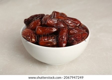 Sweet dried dates in bowl on light table