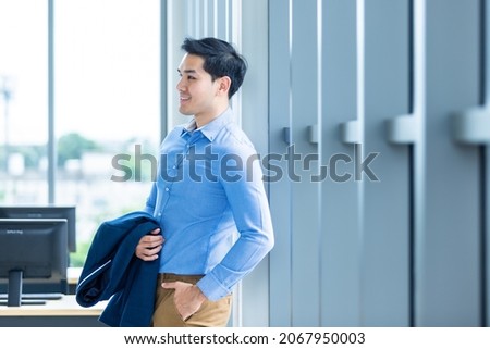 Portrait of a cheerful successful feeling winner handsome young asian businessman wear a business suit of man in blue jacket and blue shirt at window In the office room background.