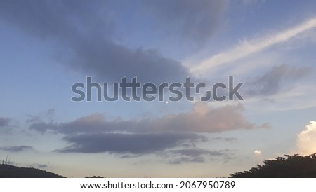 Real Photo or Picture of Blue Purple Sky with tree silhouette, moon, white and grey clouds taken in the evening