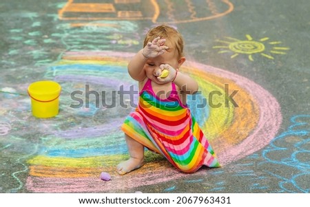 The child draws with chalk on the asphalt. Selective focus. Kid.