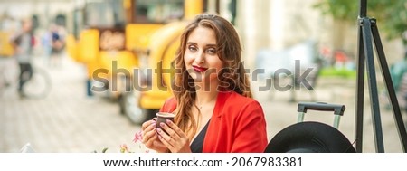 Tourist young caucasian woman in red jacket with coffee cup at the table in cafe outdoors