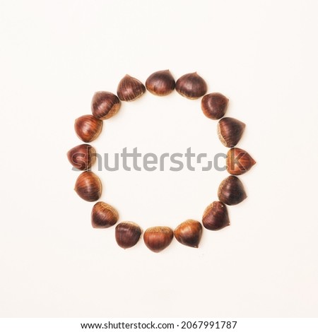 Beautiful brown chestnuts with central minimal circular creative copy space. Beige background. Minimal arrangemet.
