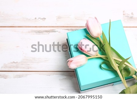 Delicate pink tulips on a turquoise gift box.