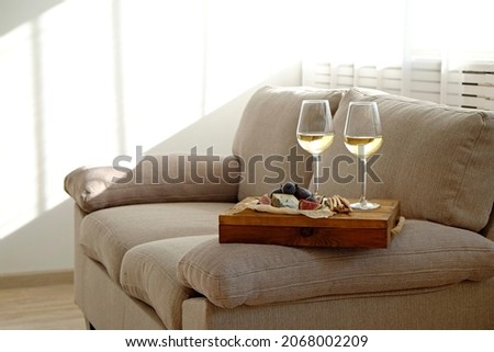 Two wineglasses of vintage chardonnay with delicious appetizers. Couple of glasses of white wine, italian breadsticks, figs and grapes. Interior background. Close up, copy space.