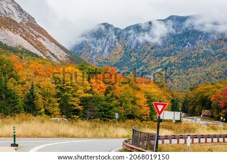 Mountain and hill view with colorful trees and yield sign.