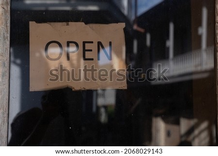 an old bar door where there is a sign behind the glass that it is open