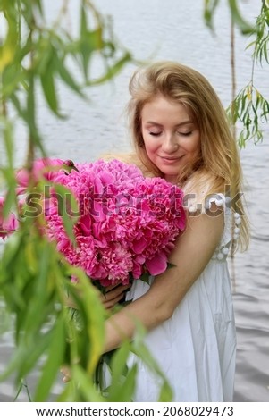Young beautiful girl with a bouquet of peonies