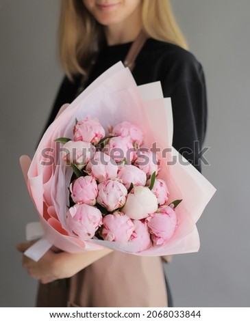 Bouquet of pink peonies. Young woman holding fresh beautiful bouquet of peony wrapped in paper. Flower gift.