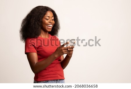 Portrait Of Young Cheerful Black Lady Using Smartphone For Messaging With Friends, Happy African American Lady Texting On Cellphone While Standing Over White Studio Background, Copy Space Royalty-Free Stock Photo #2068036658
