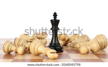 King among fallen chess pieces on wooden board against white background