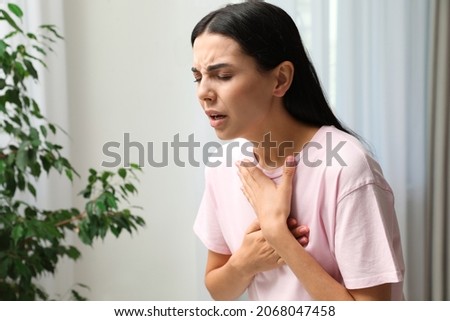 Young woman suffering from breathing problem indoors Royalty-Free Stock Photo #2068047458