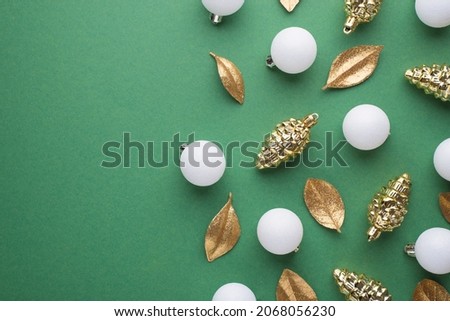 Top view photo of white christmas tree balls gold toys cones and golden leaves on isolated green background with copyspace