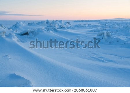 Winter arctic landscape. Ice hummocks on the frozen sea in the Arctic. View of snow and ice at sunset. Cold frosty winter weather. Harsh polar climate. Amazing nature in the far north in the Arctic.