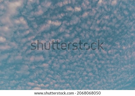 Scattered clouds of light pink color and skyblue sky stock photo.