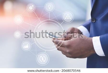 Hands of millennial african american businessman in suit typing on smartphone, double exposure with icons idea, sharing, graphics. Successful passive income, business success, dividends, investments