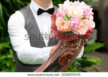 Portrait young happy man holding beautiful bouquet of autumn flowers in his hand to surprise girlfriend with Romantic gift. Valentine's day, Wedding day or anniversary concept.