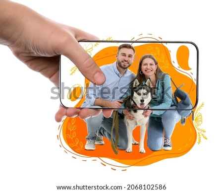 Woman with mobile phone taking photo of young couple with dog on white background