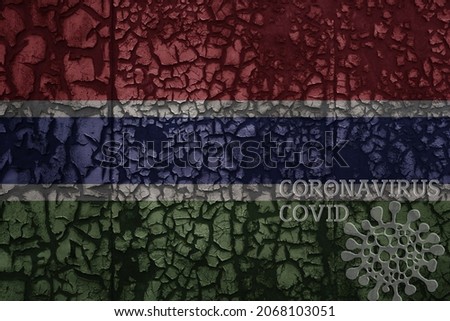 flag of gambia on a old vintage metal rusty cracked wall with text coronavirus, covid, and virus picture.