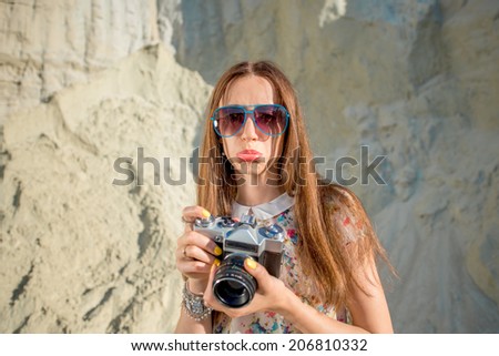 Displeased woman traveler taking photo on the sandy background