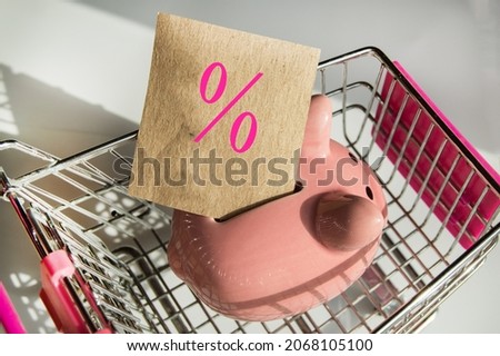 Discount season, piggy bank in the shopping cart on a white background and a paper template with a percentage sign.