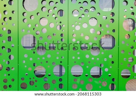 Perforated metal textured facade in bright light green color. Background for industrial design