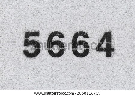Black Number 5664 on the white wall. Spray paint. Number five thousand six hundred and sixty four.