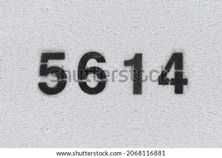 Black Number 5614 on the white wall. Spray paint. Number five thousand six hundred and fourteen.