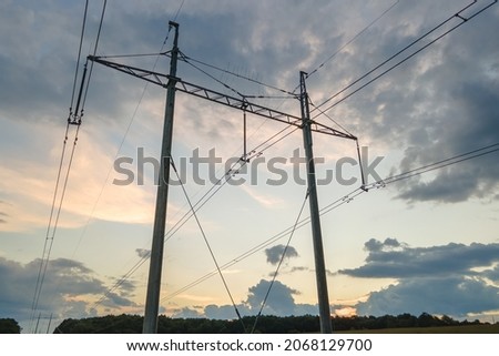 Dark silhouette of high voltage tower with electric power lines at sunrise.