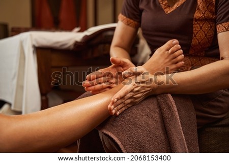 Masseuse kneading both sides of female client ankle