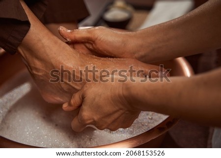 Beauty salon worker rubbing her client feet with sea salt