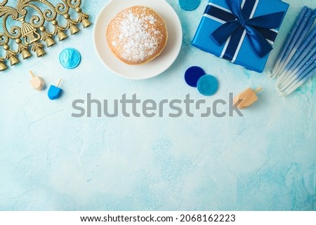 Hanukkah background with traditional donuts, menorah and gift box. Top view composition with copy space