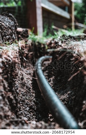Focus on a black 1 inch sprinkler plastic water line laid in a shallow trench Royalty-Free Stock Photo #2068172954