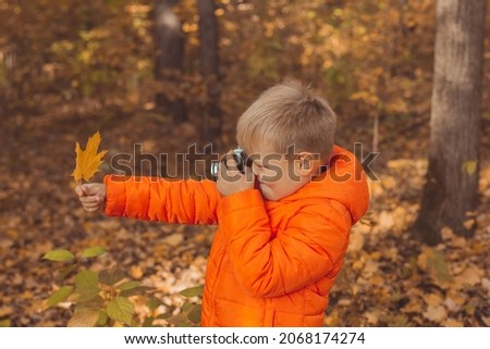 Boy with retro camera taking pictures outdoor in autumn nature. Leisure and photographers concept