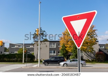 Yield give way road traffic sign on street with cars driving in Ottawa, Canada in fall