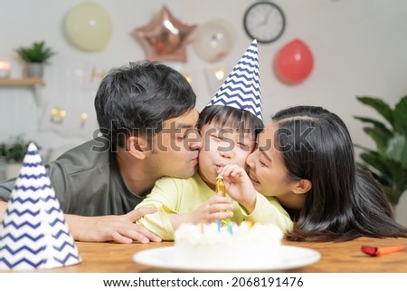Happy birthday party in family, asian young parent father, mother and little cute boy or child celebrating, blowing candles on the cake and decorated balloons, celebration at home. Lovely moments