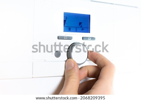Fingers adjust Gas boiler control panel for hot water and heating. Buttons and a digital display. Сoncept of home heating and heat conservation. Royalty-Free Stock Photo #2068209395