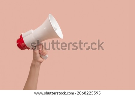 Megaphone in woman hands on a pink background. Copy space.  Royalty-Free Stock Photo #2068225595