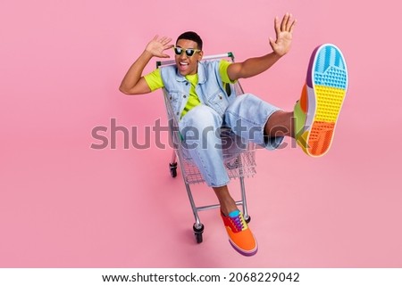 Full size photo of impressed millennial brunet guy sit in trolley wear eyewear t-shirt vest jeans shoes isolated pink background Royalty-Free Stock Photo #2068229042