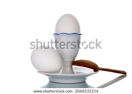 Two white chicken eggs with ceramic stand and spoon, close-up, isolated on white.