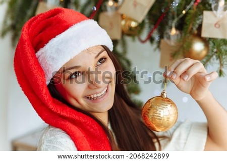 happy girl in a Christmas hat with a Christmas tree toy in her hand close-up. High quality photo