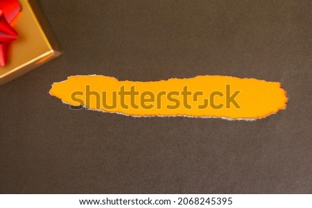 A black rectangular clothing tag rests on torn black paper. Yellow background.