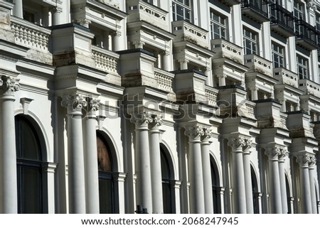 Facade of a white building with many white windows. House facade of old historical building with white walls. Exterior design of apartment building with ornamental details. High quality photo Royalty-Free Stock Photo #2068247945