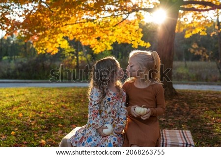 Two cute little sisters at the park in autumn