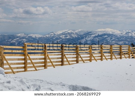 Wood fence in the snowy landscape on the mountain in the winter day.