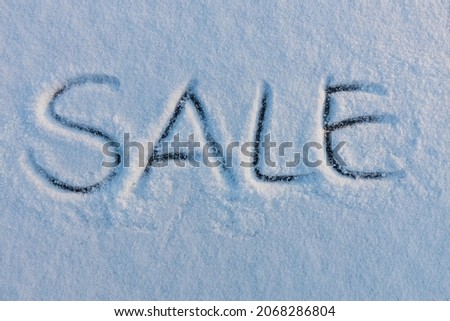 Handwritten word sale on a snowy surface. Winter holidays concept background.