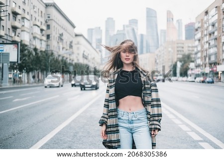 Young brunette girl in black standing outside and watching the sunset in the city, the sun shines brightly, fashionable clothes on a girl, hipster style,, tattoo, street photo, mood, freedom, New York